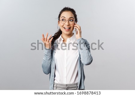 Office lifestyle, business and people concept. Talkative, amused good-looking asian woman in glasses discuss fresh gossips and news on phone, gesturing passionately talking with upbeat smile Royalty-Free Stock Photo #1698878413