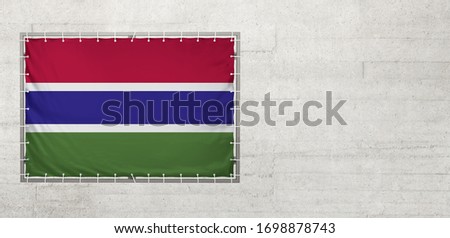 Gambia flag on a tarpaulin that is placed on a concrete wall