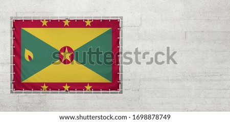 Grenada flag on a tarpaulin that is placed on a concrete wall