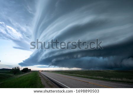 Wall cloud moving over the landscape with road during severe storm warning.