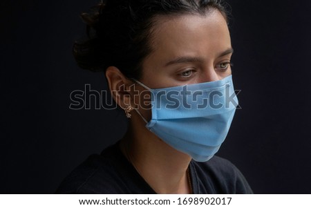 Stressed worried young woman wearing medical face mask, studio portrait. Woman wearing face mask during coronavirus outbreak. Virus spread flu prevention carantine