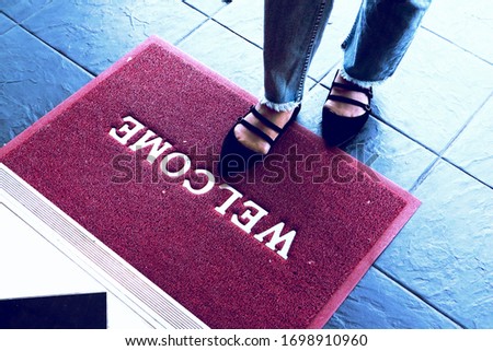 Welcome carpet with women shoes on floor.
