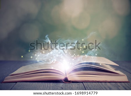 Open book with magic glowing on wooden table. Fairy tale Royalty-Free Stock Photo #1698914779