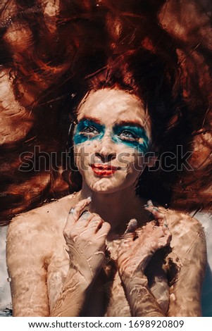 Portrait of a red-haired mermaid girl who calls everyone to her tender embrace