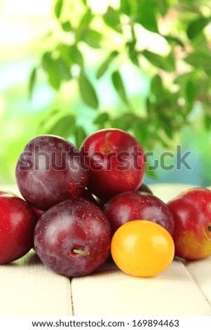 Ripe plums on wooden table on natural background
