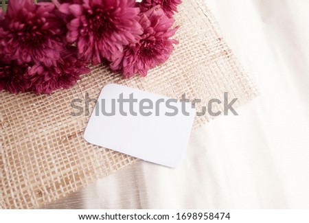 Dark pink Gerbera flowers and white paper for writing card on the wood table. Theme for invitation party or happy anniversary.