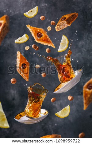 Azerbaijani sweet pakhlava. Food levitation. Azerbaijani dessert pakhlava and tea in armudu glass with lemon and hazelnuts Royalty-Free Stock Photo #1698959722