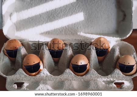 Raw brown eggs in black masks in tray alternating with empty spaces. Concept of Easter with social distancing in the quarantine during COVID-19 pandemic.
