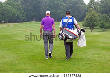 Golfer and caddy walking towards a ball on a par 4 fairway.  Royalty-Free Stock Photo #169897328