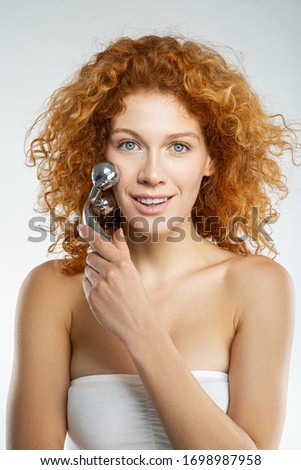 Waist up portrait of young female using 3d massager for rejuvenation isolated on white background stock photo