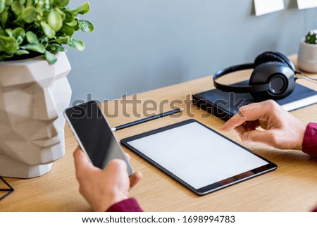 Modern business composition on the home office with freelancer, mock up tablet screen, plant, notes, mobile phone and office supplies in stylish concept of home decor.