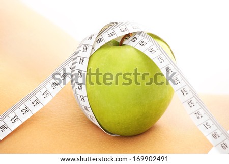 A picture of a green apple with tape measure on a female back