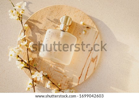
glass perfume bottle with branches of blooming sakura on a wooden plate on a light background Royalty-Free Stock Photo #1699042603