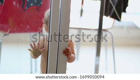 
Cute baby playing hide and seek, infant hiding behind window, toddler peeking out