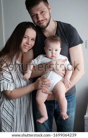 Smiling mother and father holding their newborn baby daughter at home
