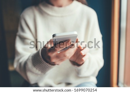 Women's hands use a smartphone for online shopping, social networking, or remote work. Close up image.