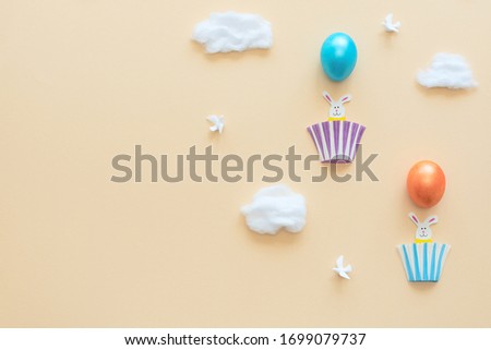 Hot air balloons made of Easter eggs with bunnies in the baskets on yellow background with clouds and birds. Happy Easter holiday concept. Greeting, invitation card. Flat lay with copy space. 