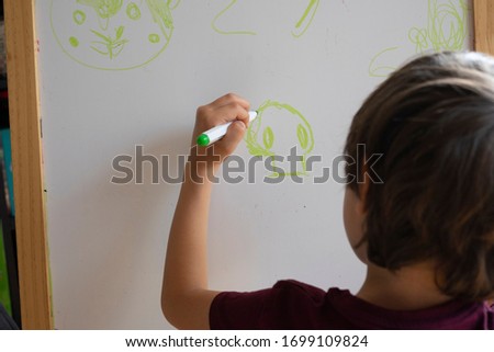 boy painting on a blackboard taking home lessons by covid-19
