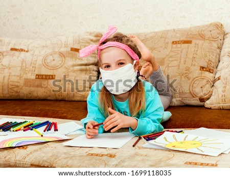 Cute girl in medical mask is sitting at home in quarantine. girl draws with pencils after disinfection of hands. Fun activities for children during quarantine. Self isolation