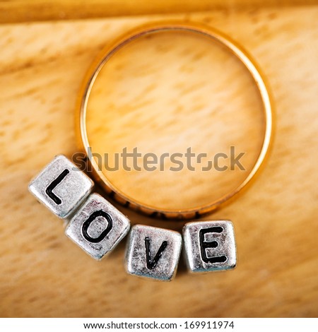 Message love spelled in metallic blocks and golden ring