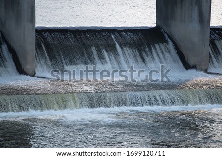 A bubbling stream of water flows through a dam during high water