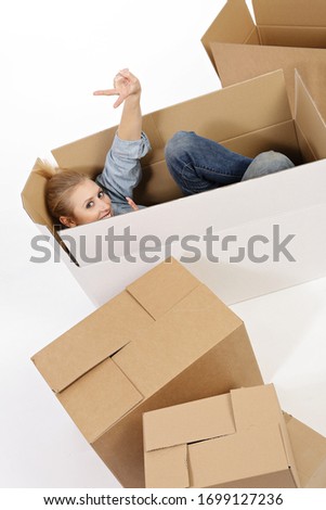 young and attractive smiling blonde woman moving and carrying cardboard moving crates on white isolated studio background
