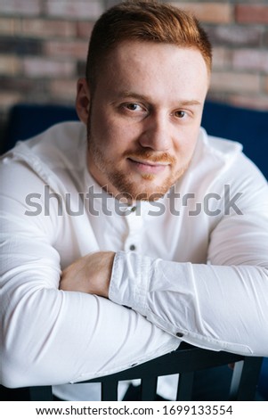 Portrait of handsome young adult man looking at camera, crossed hands.