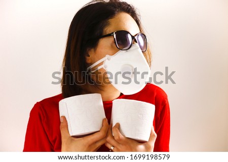 Young lady, black sunglasses and FFP3 Corona virus Covid19 protection face mask protecting rolls of toilet paper holding in hands strong. Isolated white background medical business concept. Prepping
