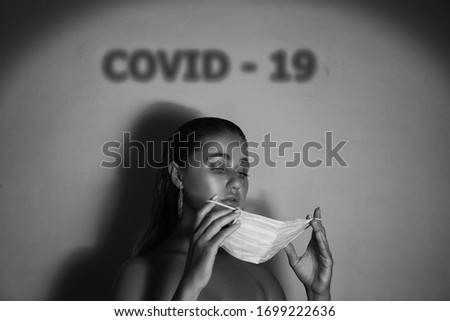 A young woman puts on a medical mask. Black and white photo. Covid-19.Coronavirus.