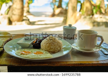 Breakfast on Boracay island of the Philippines with views of the white sandy beach and sea. An omelet and a Cup of coffee in a white dish.