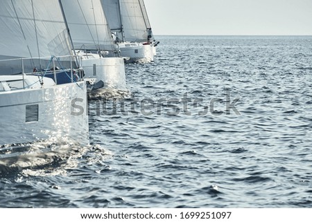 Start of race of sailing regatta, sailboats compete in a sail regatta at sunset, sun reflection on board of boat, clear weather Royalty-Free Stock Photo #1699251097