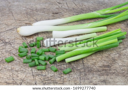 Spring green onions are on an old wooden cutting board.