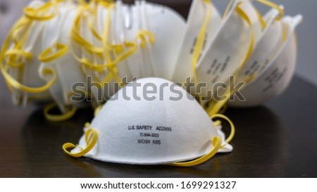 A safety n95 surgical mask sits in front of a pile of masks during the quarantine of 2020 Royalty-Free Stock Photo #1699291327
