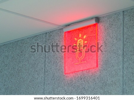 Red glowing radio symbol in the form of a microphone. The sign indicates that the sound is being broadcast on the radio, recording a track, on air.