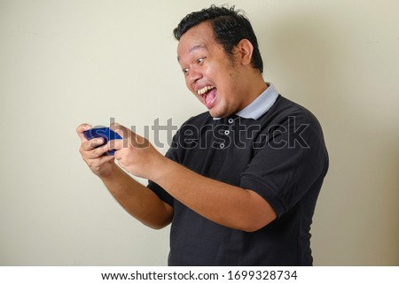 Fat Asian men feel shocked and happy when receiving news online on a smartphone with a winning gesture