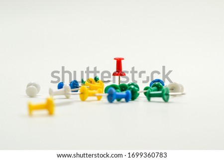 a variety of colorful pushpins and one of the red pushpins stuck to the paper