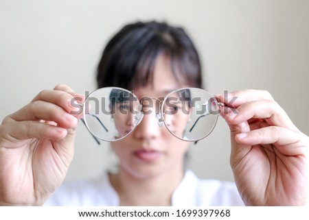 Short-sighted woman is holding glasses in hand with white background. symbolic photo for bad vision and refractive error Royalty-Free Stock Photo #1699397968