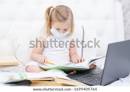 Toddler girl with laptop at home. Child watching cartoons. Kid using gadget to communicate with friends or kindergartners. Education and distance learning for kids. Stay at home entertainment