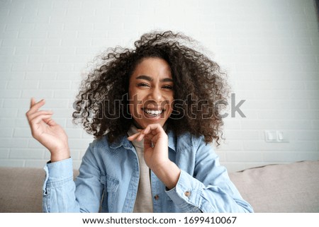 Cheerful african teenage girl blogger talking to camera recording vlog. Happy mixed race young woman laughing making video call at home. Funny social media influencer streaming blog. Webcam view. Royalty-Free Stock Photo #1699410067