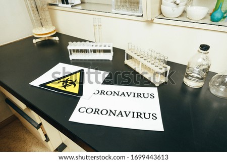 signal tape and plate with the word "coronavirus" on the laboratory bench with test tubes