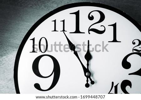 Black and white wall clock showing five minutes until 12 oclock Royalty-Free Stock Photo #1699448707