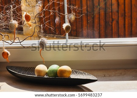 A picture of easter decoration with colorful eggs and small eggs hanging above them