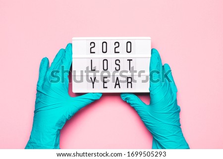 2020 lost year concept. Hands in turquoise medical gloves hold lightbox with text 2020 lost year. Concept of lost goals during pandemic of coronavirus.