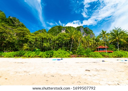 Famous Railay beach at Krabi town, Thailand. View of white sand and the jungle in background. Tropical plants, trees and palms. Famous vacation target.
