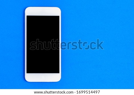 White mobile phone with a black screen on a blue background.