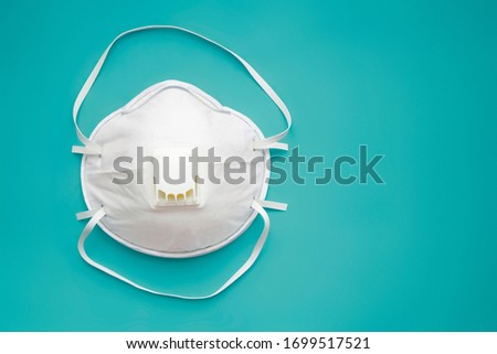 White face medical mask against virus, flu and coronavirus isolated on turquoise background. Protective respirator with valve. Royalty-Free Stock Photo #1699517521