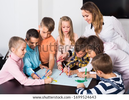 Professor and group of elementary age children drawing together one picture