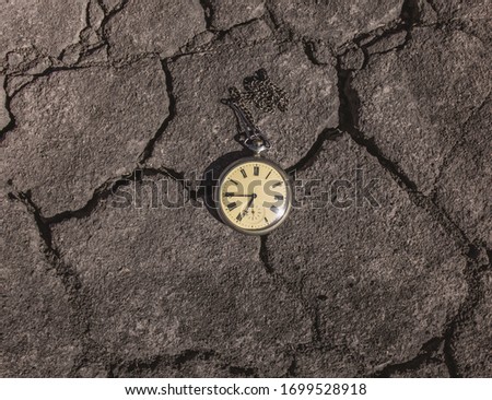 Retro vintage antique clock pocket watch, lie on a background of dry earth. The concept of past or future tense.