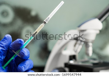 Virologist's hand in glove holding syringe.