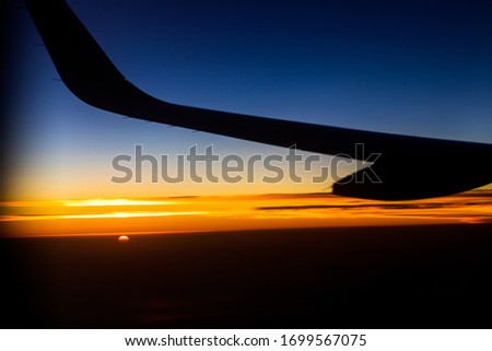 Airplane wing silhouette with sunset background, photo through airplane window